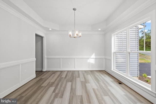 spare room with ornamental molding, an inviting chandelier, light hardwood / wood-style floors, and a healthy amount of sunlight