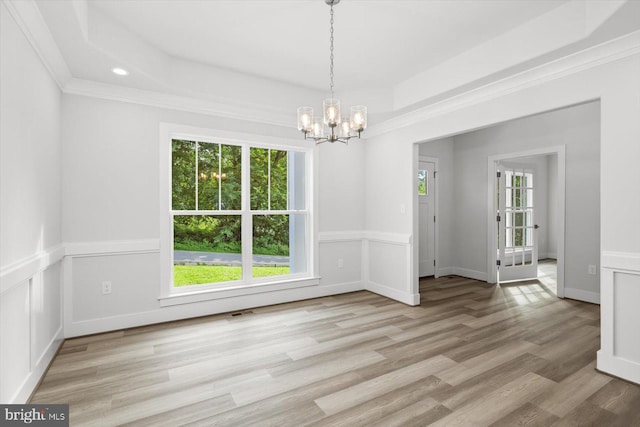 spare room featuring an inviting chandelier, light wood-type flooring, and ornamental molding