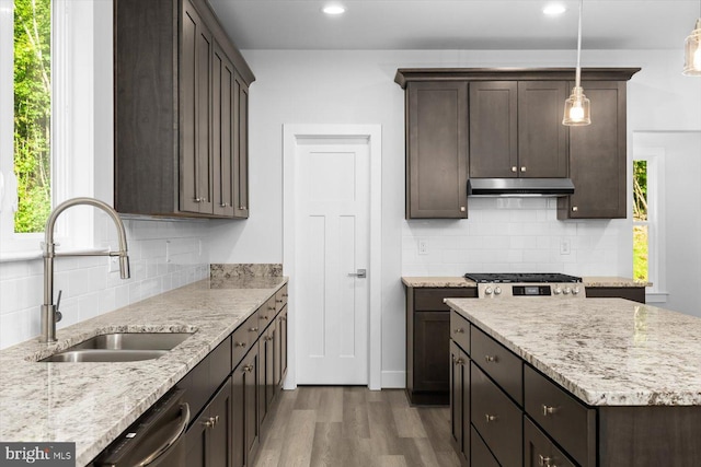 kitchen with light stone countertops, hanging light fixtures, sink, and dark hardwood / wood-style flooring