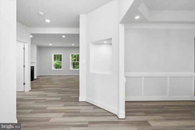 corridor with light wood-type flooring and ornamental molding