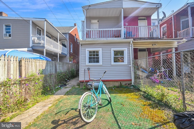 back of house with a balcony and a lawn