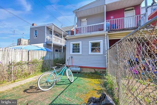 back of property featuring a balcony and a yard