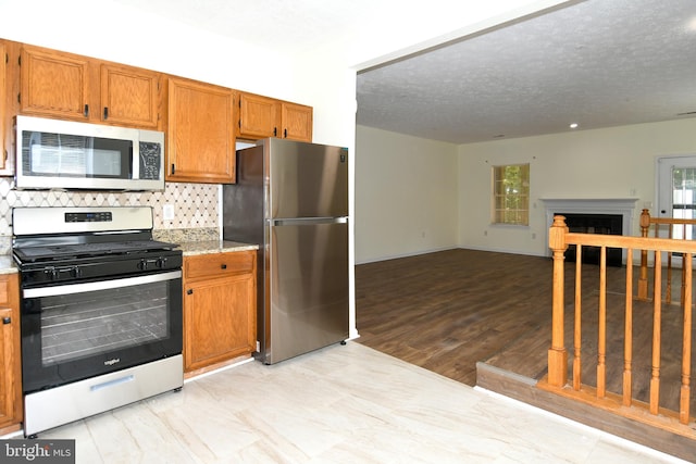 kitchen with decorative backsplash, a wealth of natural light, light hardwood / wood-style floors, and appliances with stainless steel finishes