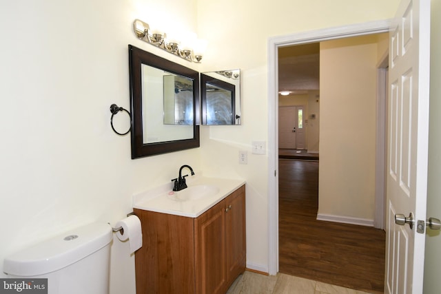 bathroom with vanity, toilet, and hardwood / wood-style flooring