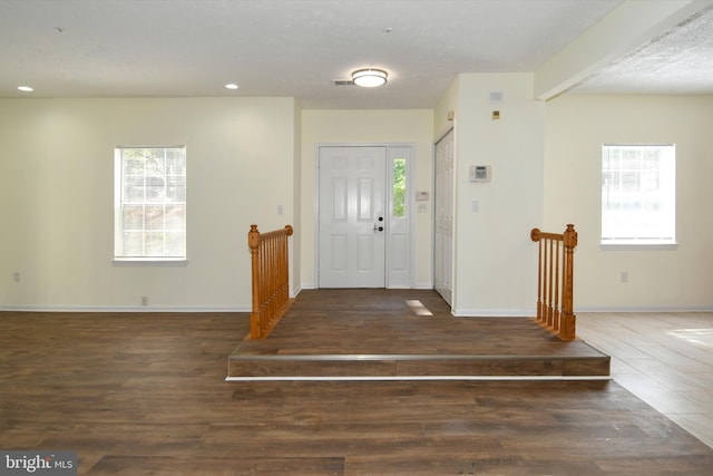 entryway featuring a textured ceiling, beam ceiling, and dark wood-type flooring