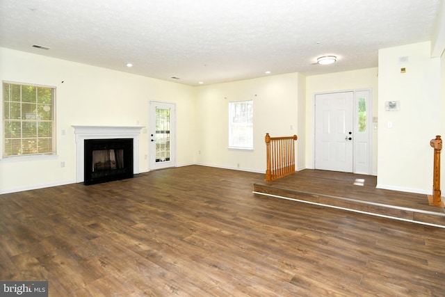 unfurnished living room featuring a textured ceiling and dark hardwood / wood-style flooring