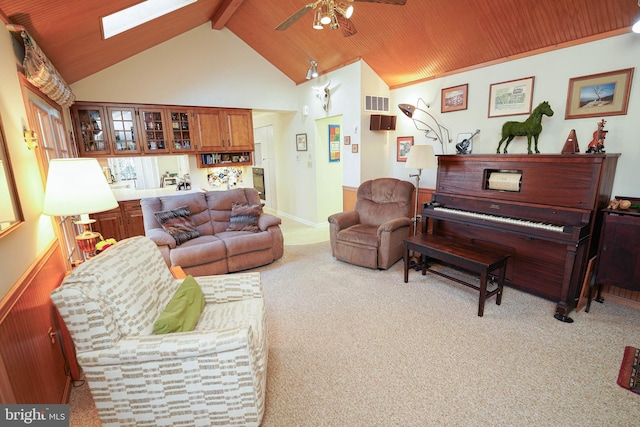 living room with ceiling fan, light colored carpet, beam ceiling, and a skylight