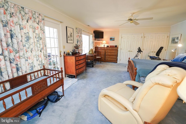 carpeted bedroom featuring ceiling fan, crown molding, and two closets