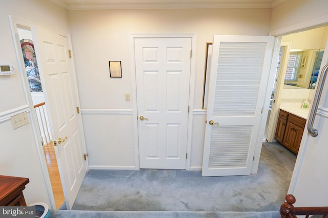 hall with ornamental molding and light colored carpet