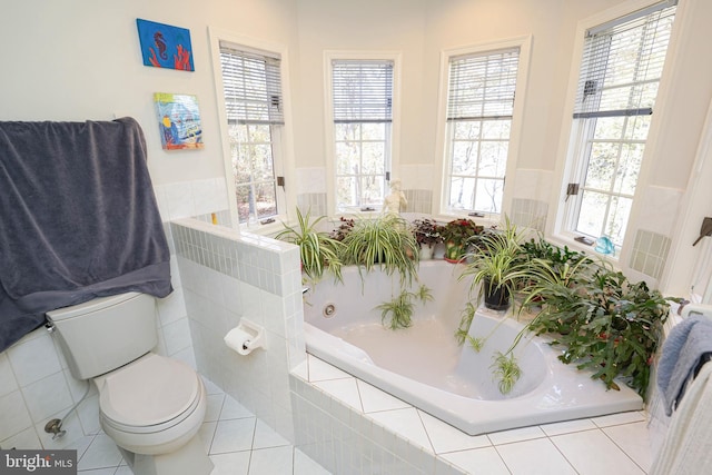 bathroom with toilet, a relaxing tiled tub, and a healthy amount of sunlight