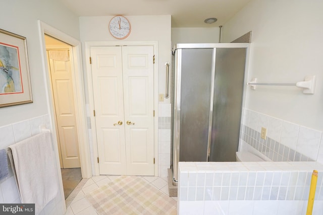 bathroom featuring tile walls, tile patterned floors, and a shower with door