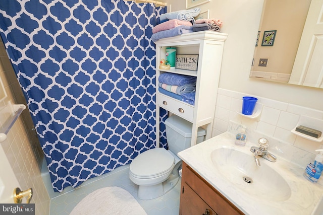 bathroom featuring toilet, vanity, tile walls, and tile patterned floors