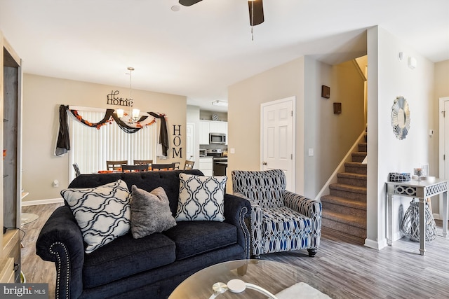 living room featuring ceiling fan with notable chandelier and light hardwood / wood-style floors