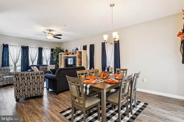 dining space featuring ceiling fan with notable chandelier and dark hardwood / wood-style floors