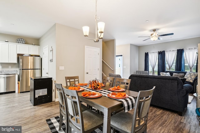 dining area with ceiling fan with notable chandelier and light wood-type flooring