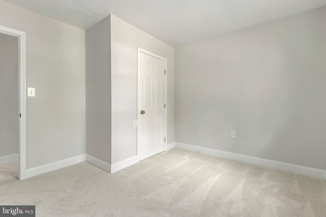 unfurnished bedroom featuring light carpet and baseboards