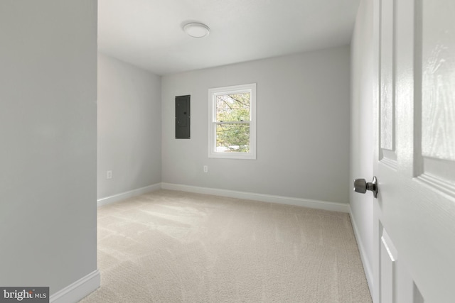 spare room featuring electric panel, light carpet, and baseboards