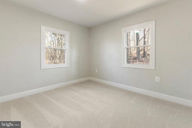 unfurnished room with baseboards and light carpet