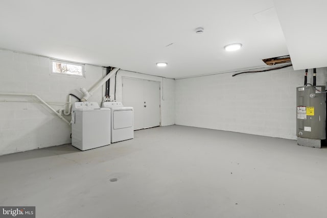 below grade area featuring washer and dryer, concrete block wall, and water heater