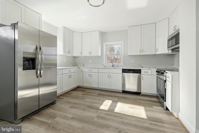 kitchen featuring light wood finished floors, appliances with stainless steel finishes, white cabinetry, and light countertops