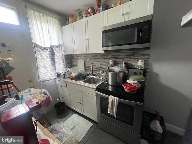 kitchen featuring stainless steel appliances, white cabinetry, tasteful backsplash, and sink