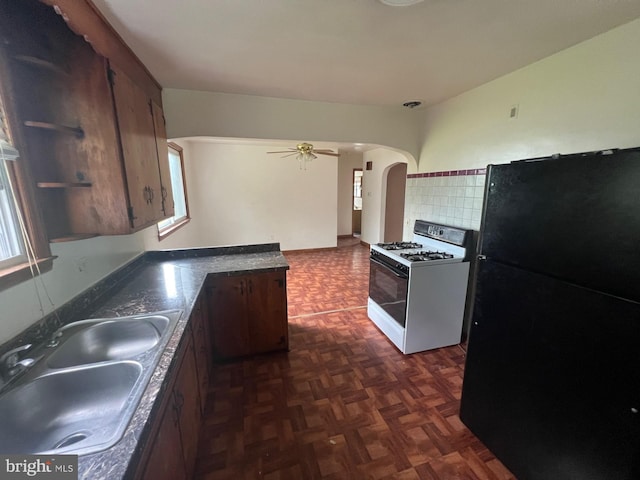 kitchen featuring ceiling fan, black fridge, sink, tasteful backsplash, and white gas range