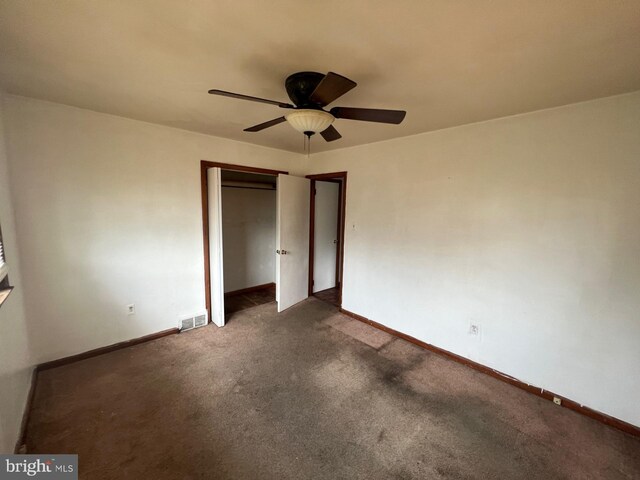 unfurnished bedroom with dark carpet and ceiling fan