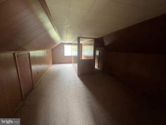 bonus room with carpet floors, lofted ceiling, and wood walls