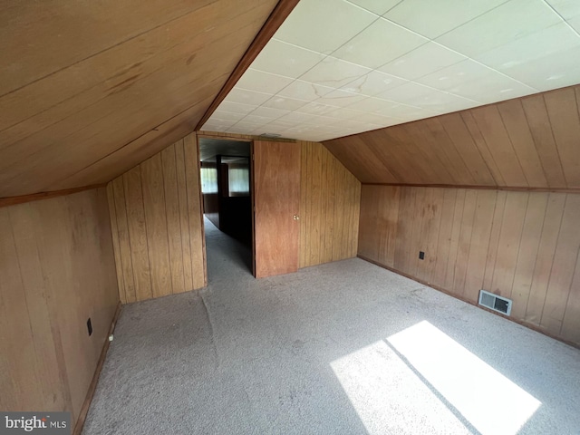 bonus room featuring wooden walls, lofted ceiling, and light colored carpet