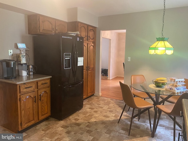 kitchen featuring decorative light fixtures, light hardwood / wood-style floors, and black fridge with ice dispenser