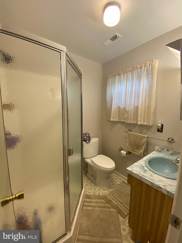 bathroom with vanity, tile patterned flooring, toilet, and a shower with door