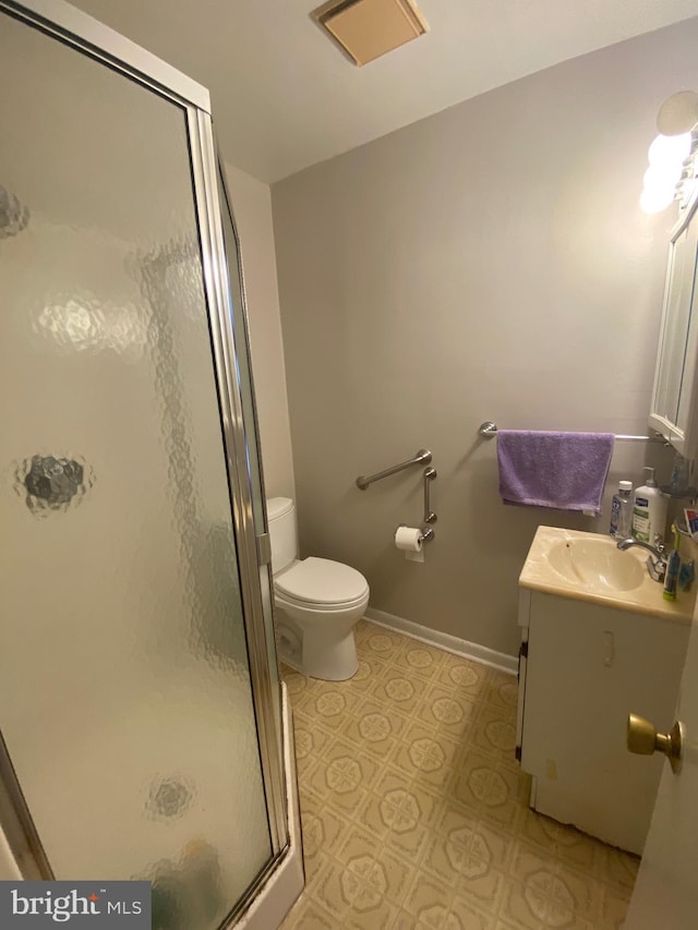 bathroom featuring vanity, toilet, and a shower with door