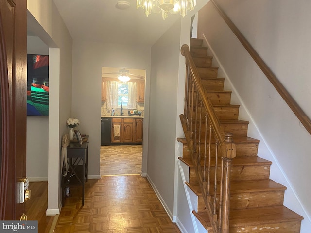 stairway featuring an inviting chandelier and parquet floors