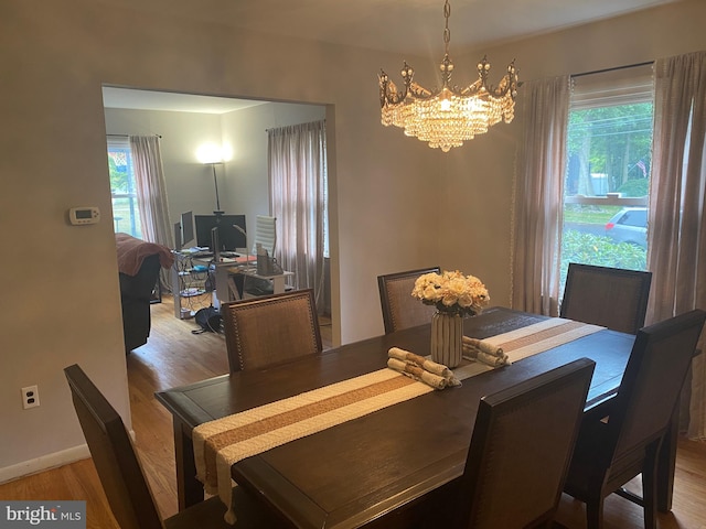 dining area featuring a healthy amount of sunlight, light hardwood / wood-style flooring, and a chandelier