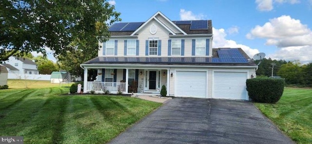 view of front facade featuring covered porch, a front yard, solar panels, and a garage