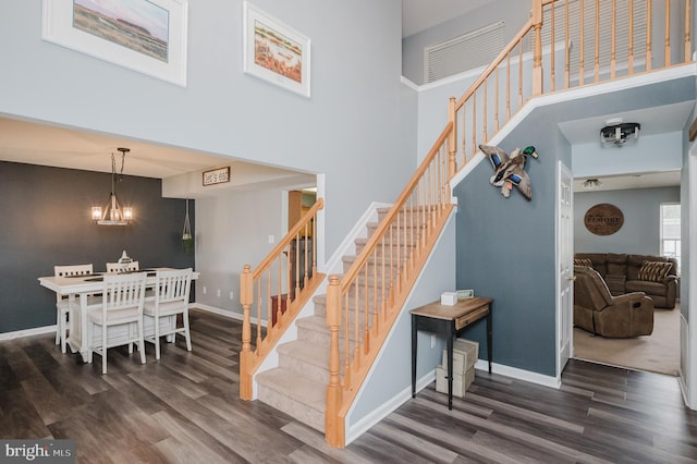 stairway featuring a notable chandelier, a towering ceiling, and wood-type flooring