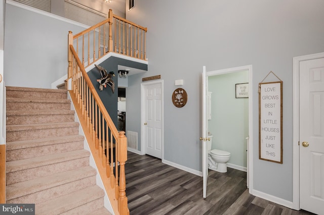 stairway featuring wood-type flooring and a high ceiling