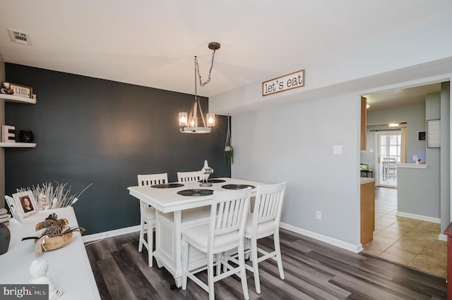 dining space with dark wood-type flooring and a chandelier