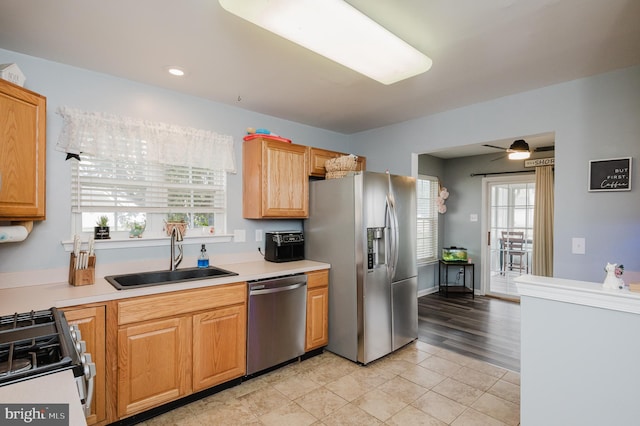 kitchen featuring appliances with stainless steel finishes, sink, light wood-type flooring, and ceiling fan