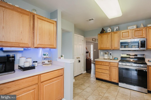 kitchen with light tile patterned flooring, stainless steel appliances, and light brown cabinetry