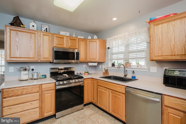 kitchen with light tile patterned floors, stainless steel appliances, light brown cabinetry, and sink