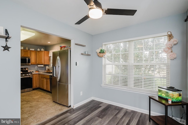 kitchen with appliances with stainless steel finishes, ceiling fan, and light hardwood / wood-style floors