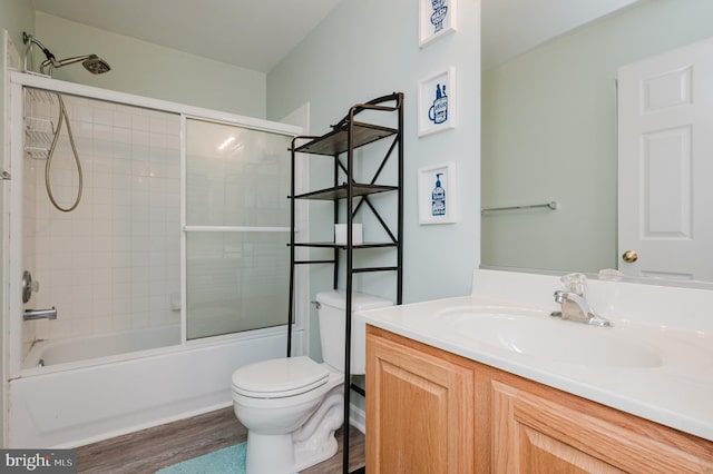 full bathroom featuring vanity, toilet, wood-type flooring, and bath / shower combo with glass door