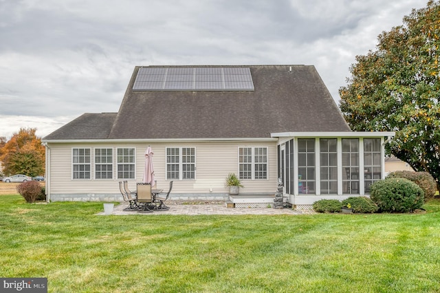 back of house with a patio, a sunroom, a lawn, and solar panels