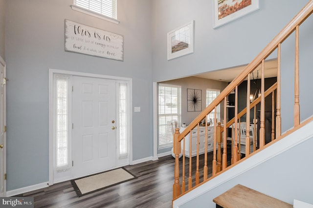 foyer entrance featuring a towering ceiling and dark hardwood / wood-style flooring