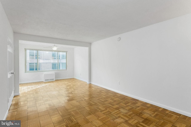 unfurnished room with a textured ceiling, light parquet floors, and ceiling fan