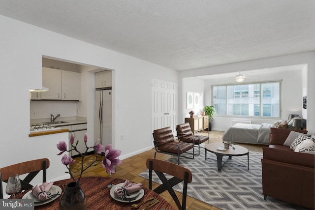 living room with a textured ceiling, sink, ceiling fan, and dark parquet flooring