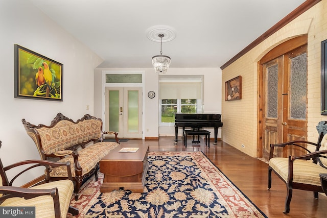 living room with brick wall, a notable chandelier, dark hardwood / wood-style floors, and french doors