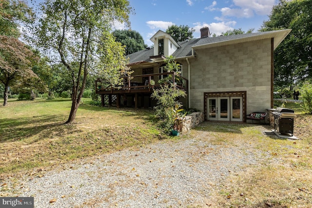 view of side of property featuring a wooden deck, french doors, and a lawn