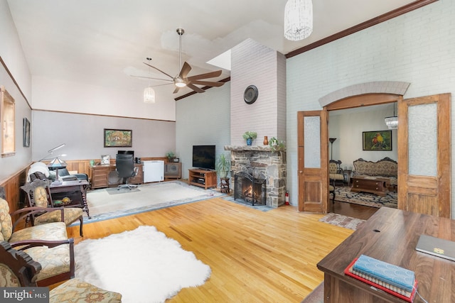 living room featuring high vaulted ceiling, ceiling fan, hardwood / wood-style flooring, and a fireplace